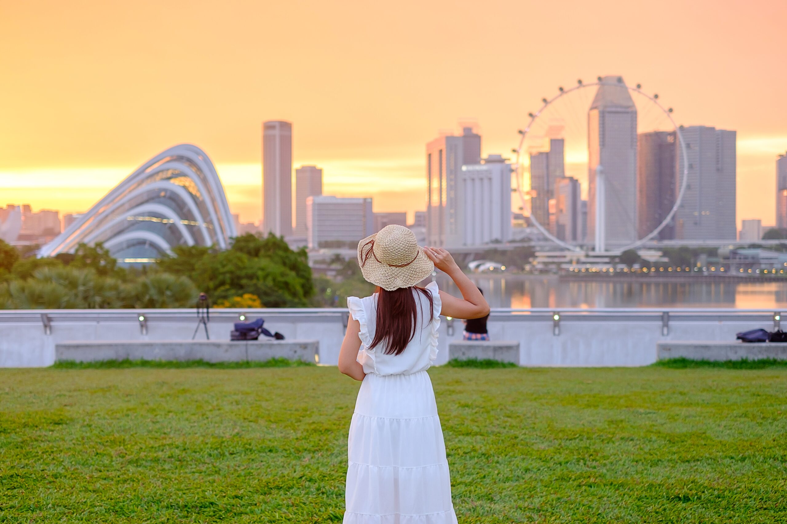 Young Woman traveling with hat at Sunset, happy Asian traveler in Singapore city